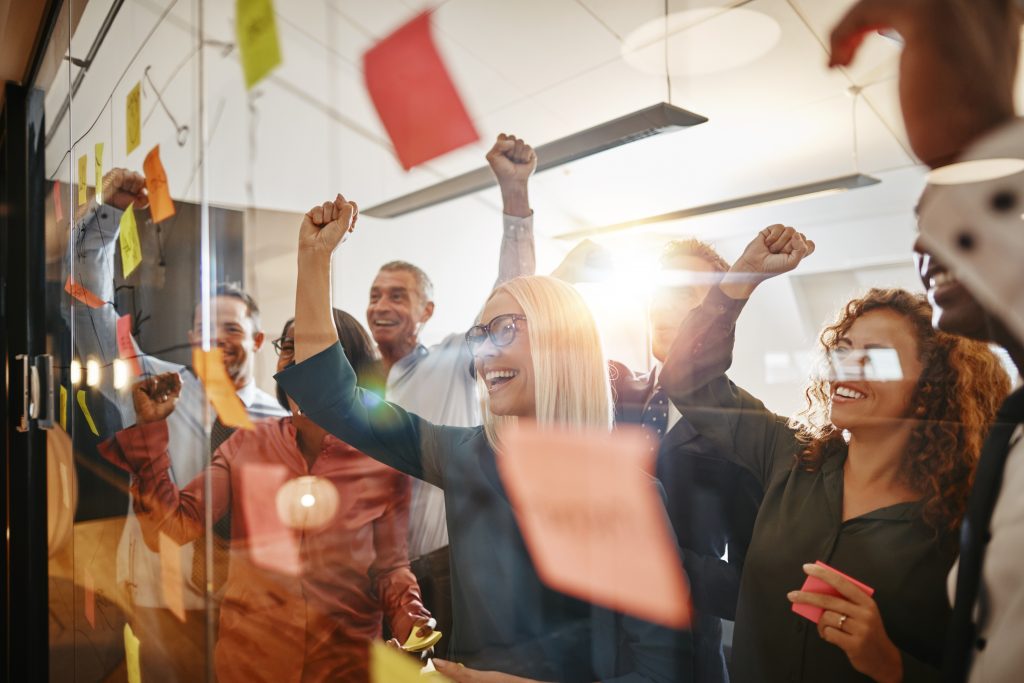 Cheering businesspeople brainstorming with sticky notes in an office